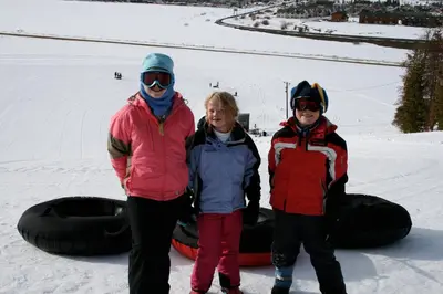a woman and two children standing in the snow next to a snowboard at Luxury in Downtown Winter Park СО in Winter Park