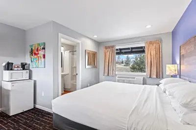 a bedroom with a large white bed and a window at Coyote Mountain Lodge in Estes Park