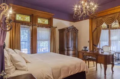 a bedroom with a bed and a desk and windows at Patterson Inn in Denver