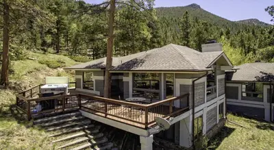 a house with a deck with a grill at Tranquil Duplex Home in Estes Park