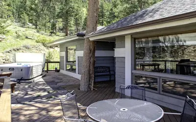 a deck with a table and chairs on a house at Tranquil Duplex Home in Estes Park