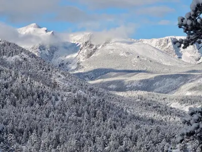 a snowy mountain range with trees and snow covered mountains at Tranquil Duplex Home in Estes Park