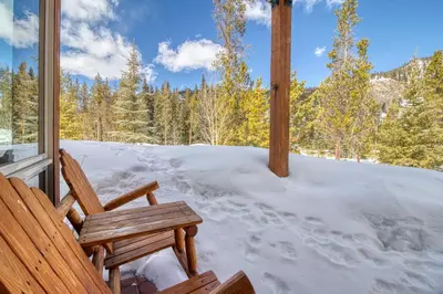 a wooden bench sitting on a porch in the snow at Settler's Creek 6524 in Keystone