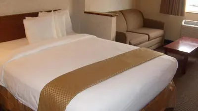 a hotel room with a bed and a chair at Baymont by Wyndham Golden/Red Rocks in Lakewood