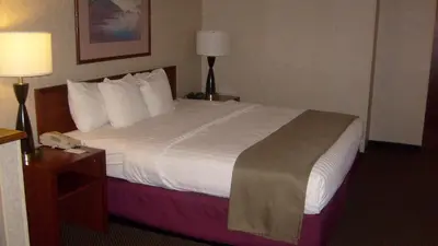 a hotel room with a large bed with white sheets at Baymont by Wyndham Golden/Red Rocks in Lakewood