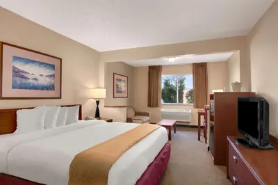 a hotel room with a large bed and a television at Baymont by Wyndham Golden/Red Rocks in Lakewood