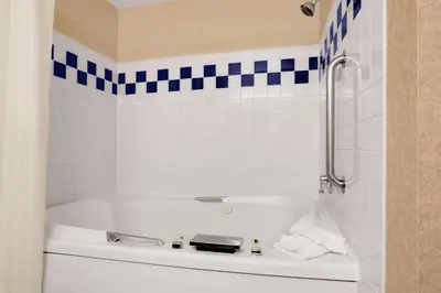 a white tub in a bathroom with blue and white tiles at Baymont by Wyndham Golden/Red Rocks in Lakewood