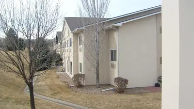 a white building with trees in front of it at Baymont by Wyndham Golden/Red Rocks in Lakewood