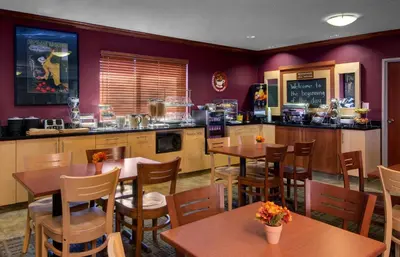 a restaurant with tables and chairs and a kitchen at Baymont by Wyndham Golden/Red Rocks in Lakewood
