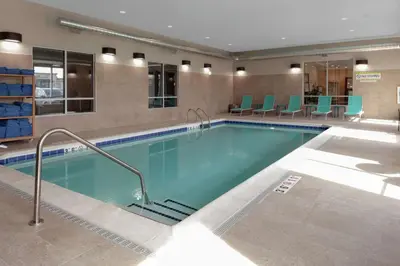 a pool in a hotel room with blue chairs at Home2 Suites By Hilton Denver South Centennial Airport in Centennial