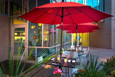 two tables with red umbrellas in front of a building at SpringHill Suites by Marriott Denver Downtown in Denver