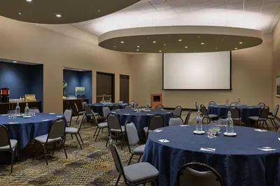 a conference room with blue tables and chairs and a screen at SpringHill Suites by Marriott Denver Downtown in Denver