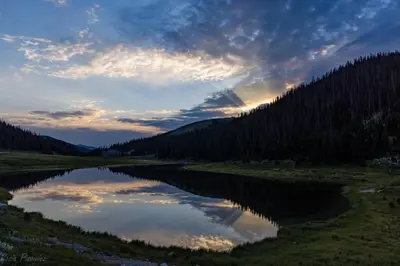 a lake in the middle of a field with trees at Mount Chiquita 10A Condo in Estes Park