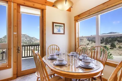 a dining room with a table and chairs and windows at Comanche Peak 39 Condo in Estes Park