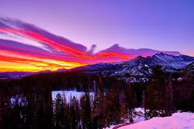 a sunset over a mountain range with trees and a lake at Bighorn Mountain 19B Condo in Estes Park