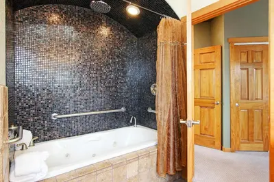 a bath tub in a bathroom with a tiled wall at Mount Cairns 16A Condo in Estes Park