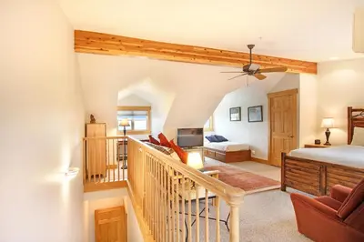 a bedroom with a staircase leading to a bed and a living room at Mount Chapin S4 Condo in Estes Park