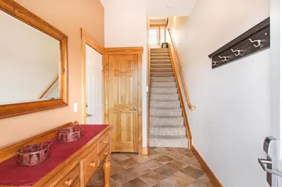 a hallway with a staircase with a mirror and a wooden door at Mount Chapin S4 Condo in Estes Park