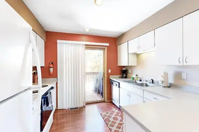 a kitchen with orange walls and white cabinets at Lagoon 737C in Frisco
