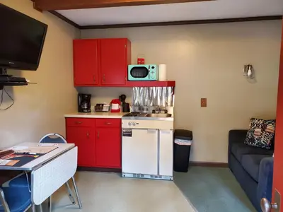 a small kitchen with red cabinets and a white refrigerator at Swiftcurrent Lodge in Estes Park