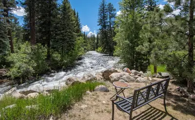 a bench sitting in front of a river at Swiftcurrent Lodge in Estes Park
