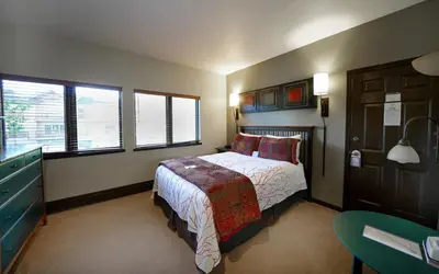 a bedroom with a bed and a desk and windows at Frisco Inn on Galena in Frisco