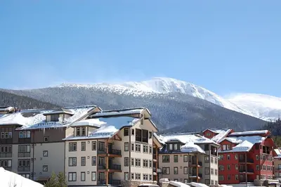 a group of buildings with snow covered mountains in the background at Fraser Crossing and Founders Pointe in Winter Park