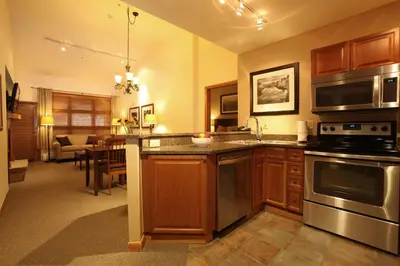 a kitchen with wooden cabinets and stainless steel appliances at Zephyr Mountain Lodge in Winter Park