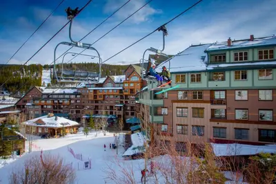 a person is riding a ski lift in the snow at Zephyr Mountain Lodge in Winter Park