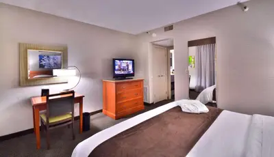a hotel room with a bed and a desk and a television at Embassy Suites by Hilton Denver Central Park in Denver