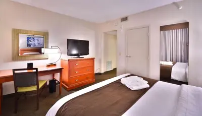 a hotel room with a bed and a desk and a television at Embassy Suites by Hilton Denver Central Park in Denver
