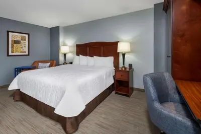 a hotel room with a large bed and a chair at Hampton Inn Denver-International Airport in Denver