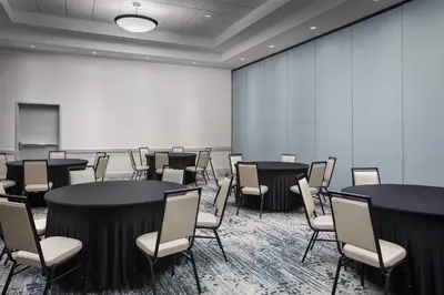 a room with tables and chairs and a white wall at Hilton Garden Inn Denver Downtown in Denver