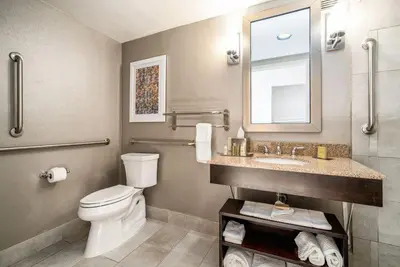 a bathroom with a toilet and a sink and a mirror at DoubleTree by Hilton Denver/Westminister in Westminster
