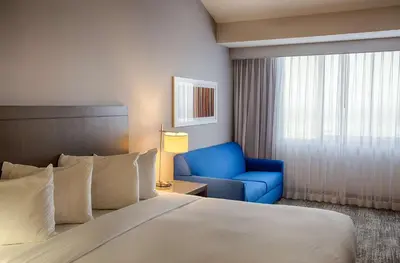 a hotel room with a bed and a blue chair at DoubleTree by Hilton Denver/Westminister in Westminster