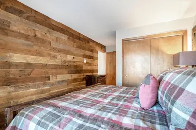 a bedroom with a bed with a wooden wall at Salt Lick #4812 - Wildernest in Silverthorne