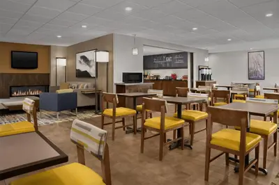 a restaurant with tables and yellow chairs and a waiting room at Hampton Inn & Suites Denver Tech Center in Centennial
