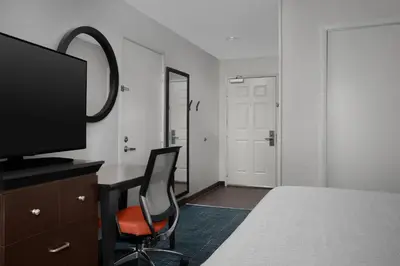 a bedroom with a desk with a television and a chair at Hampton Inn & Suites Denver Tech Center in Centennial