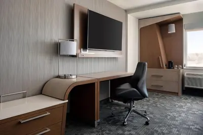 a room with a desk with a chair and a television at Courtyard by Marriott Loveland Fort Collins in Loveland