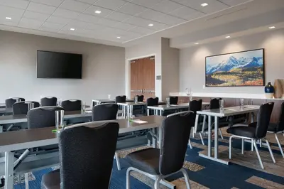 a conference room with tables and chairs and a flat screen tv at Courtyard by Marriott Loveland Fort Collins in Loveland