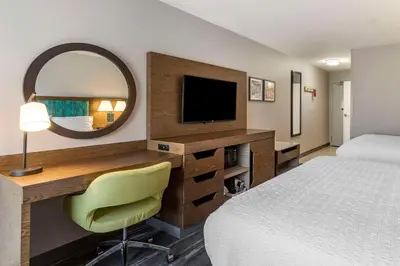 a hotel room with a bed and a desk with a mirror at Hampton Inn Fort Collins in Fort Collins