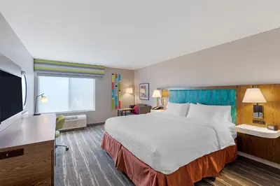 a hotel room with a bed and a flat screen tv at Hampton Inn Fort Collins in Fort Collins