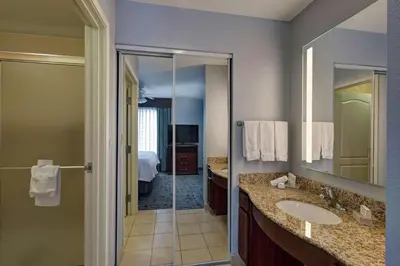 a bathroom with a shower and a sink and a mirror at Homewood Suites by Hilton Fort Collins in Fort Collins
