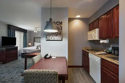a kitchen with a table and a room with a bed at Homewood Suites by Hilton Fort Collins in Fort Collins