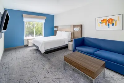 a hotel room with a bed and a blue couch at Holiday Inn Express & Suites Denver North - Thornton by IHG in Thornton