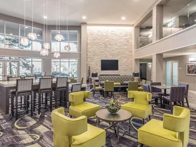 a waiting room with tables and chairs and a tv at La Quinta by Wyndham Denver Tech Center in Greenwood Village