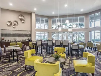 a restaurant with yellow chairs and tables and windows at La Quinta by Wyndham Denver Tech Center in Greenwood Village