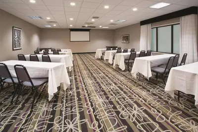 a conference room with tables and chairs and a screen at La Quinta by Wyndham Denver Englewood Tech Ctr in Greenwood Village
