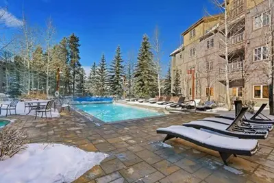 a swimming pool with a bunch of chairs next to a building at 1 Bedroom Colorado Vacation Rental In River Run Village Steps From The River Run Gondola in Keystone