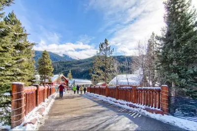 people walking on a wooden bridge in the snow at 1 Bedroom Silvermill Rental In River Run Village Steps From The River Run Gondola in Dillon